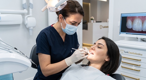 Close-up photograph of a skilled female dentist carefully sculpting and layering composite resin on a patient's front teeth, emphasizing the manual artistry in a modern Istanbul clinic.