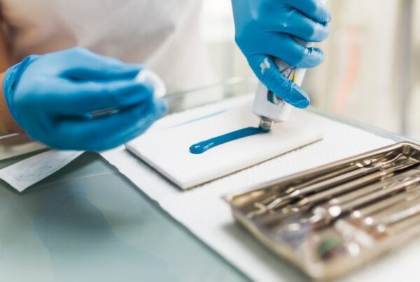 Professionista dentale a Istanbul che prepara il materiale blu per impronte su un pad sterile con strumenti nelle vicinanze, illustrando i protocolli di igiene e sterilizzazione nelle cliniche.